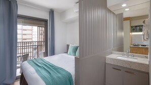 Ein Hotelzimmer mit Bett, einem Badezimmer mit Waschbecken und Spiegel sowie einem Balkon mit Blick auf die Stadt.