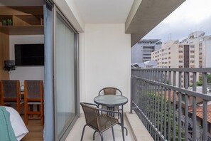 A balcony with a table and chairs, a TV mounted on the wall, and a view of the cityscape. - H.Paulista (São Paulo)