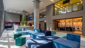 Eine moderne Hotelhalle mit Sitzbereichen, einer sichtbaren Wäscherei und einer Rezeption.