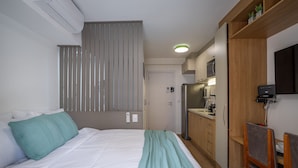 Ein Schlafzimmer mit Bett, Nachttisch, Schreibtisch mit Stuhl, einer Küchenzeile und einem Badezimmer.