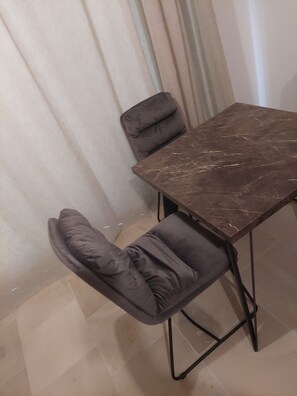A dining area with a marble table and two cushioned chairs.