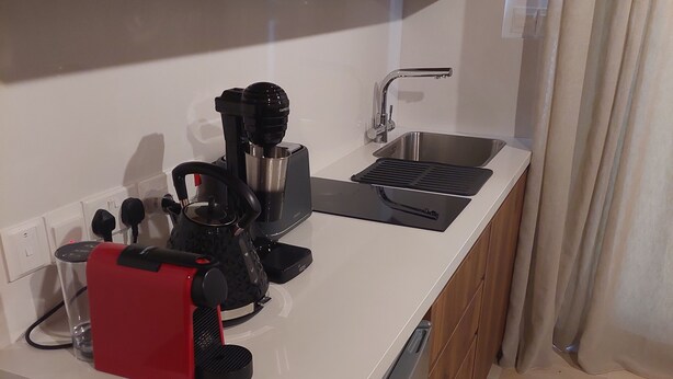 A compact kitchen with a built-in dishwasher, a coffee machine, and a sink.