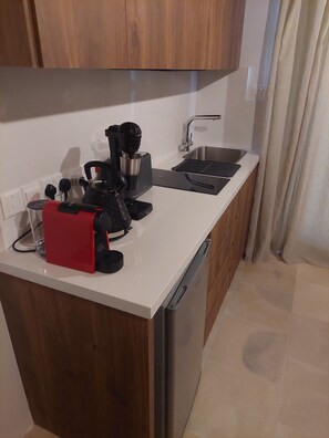 A compact kitchen with a built-in dishwasher, a coffee machine, and a sink.