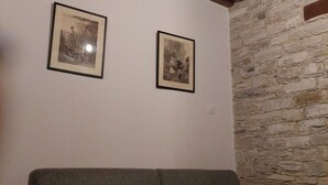 A room with a stone wall, a wooden ceiling beam, and two framed pictures on the wall.