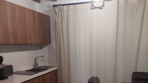 A compact kitchen with wooden cabinets, a sink, and a refrigerator. There is a dining area with a table and chairs.