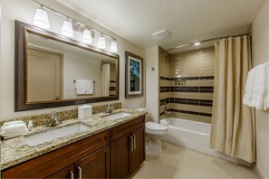 Bathroom features a double sink vanity, bathtub, and toilet with a decorative tile backsplash.