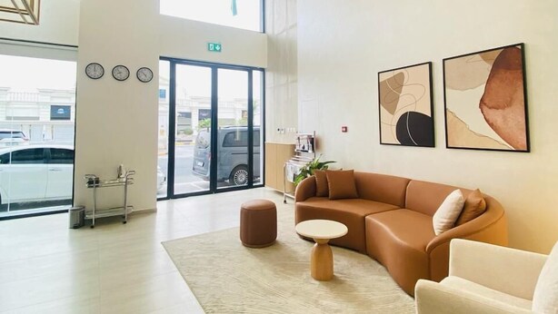 A spacious lobby with a large seating area, a reception desk, and artwork on the walls. - Baithans Furnished Apartments (Ajman)