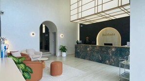 A modern reception area with a marble counter, a reception desk, and a seating area with a sofa and ottoman. - Baithans Furnished Apartments (Ajman)