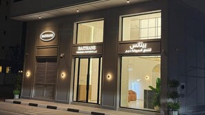 A building with a sign reading "BAITHANS" and another sign in a different language. - Baithans Furnished Apartments (Ajman)