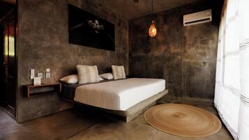 A modern bedroom with a bed, bedside tables, a wall-mounted air conditioner, and a hanging light fixture.