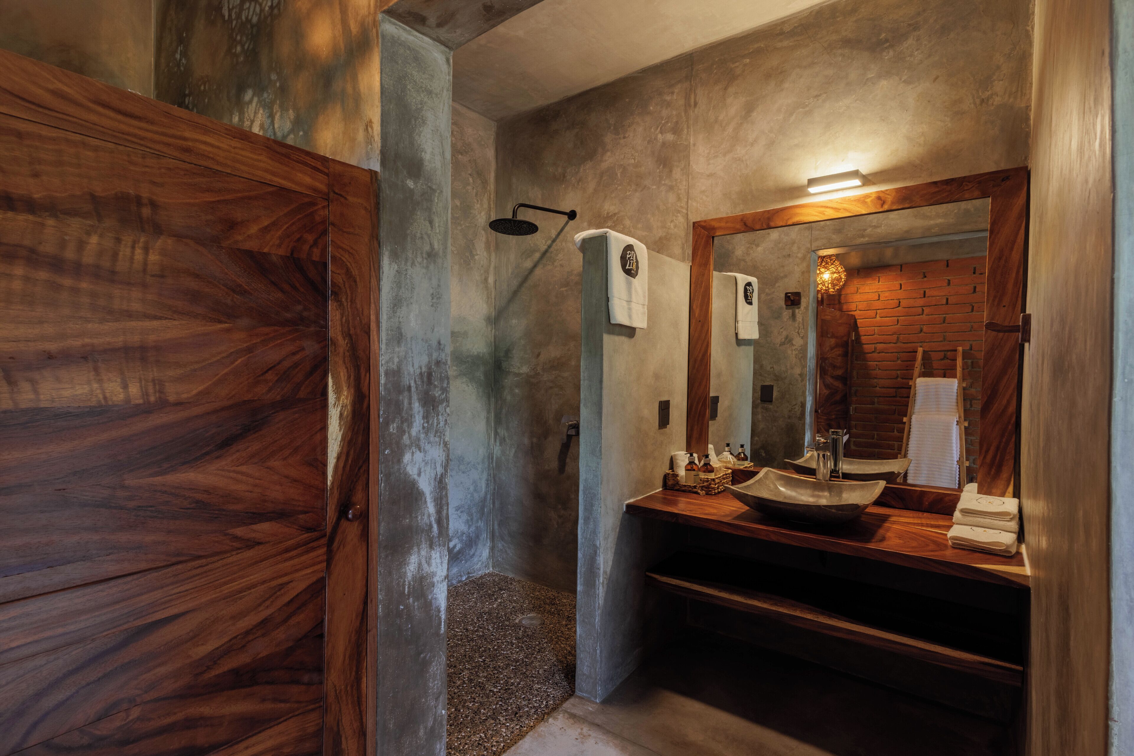 Un bagno con un mobile vanitario in legno, uno specchio grande e uno spazio doccia.