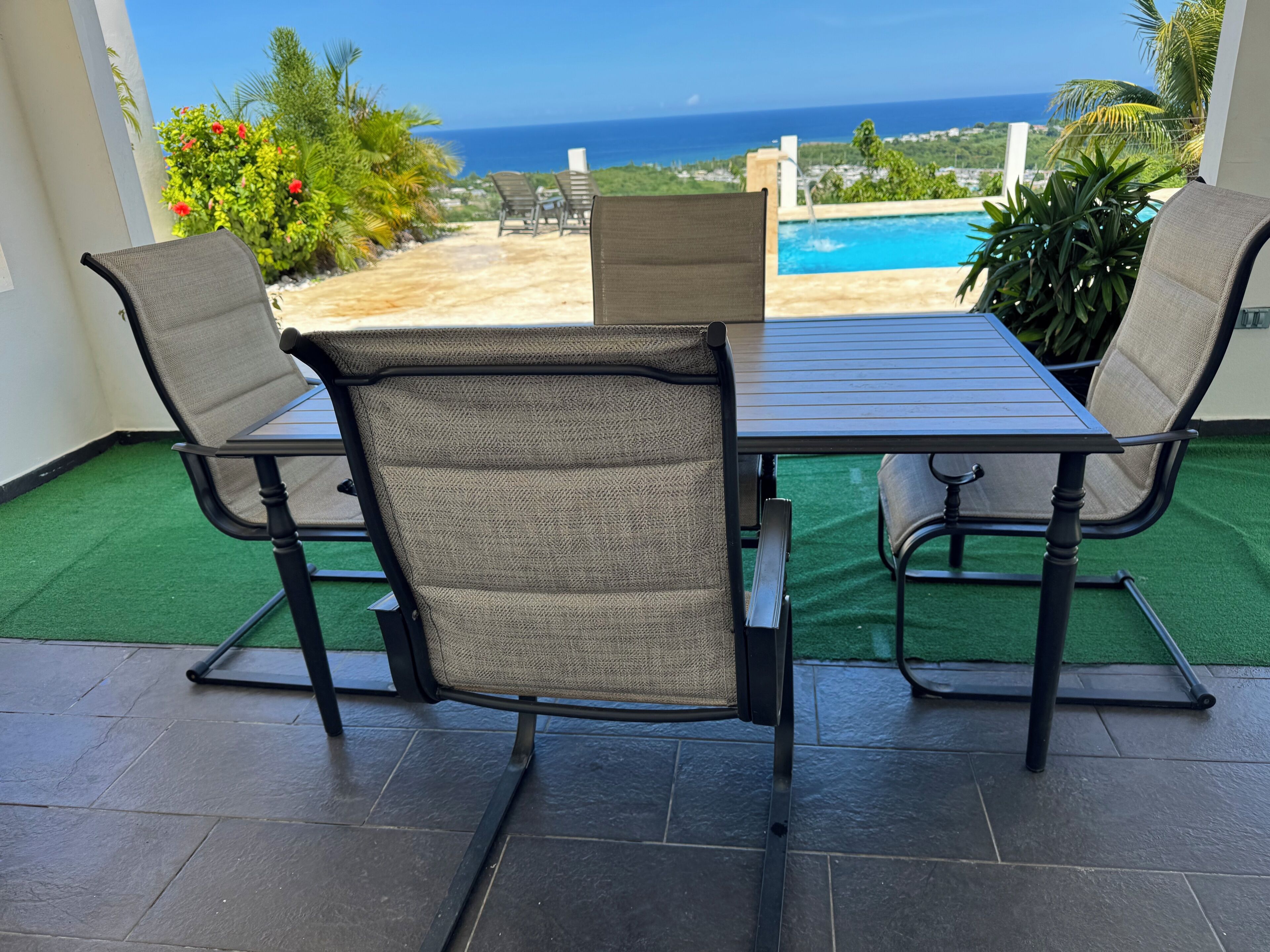 A patio with a table and chairs, a view of the ocean, and a pool.