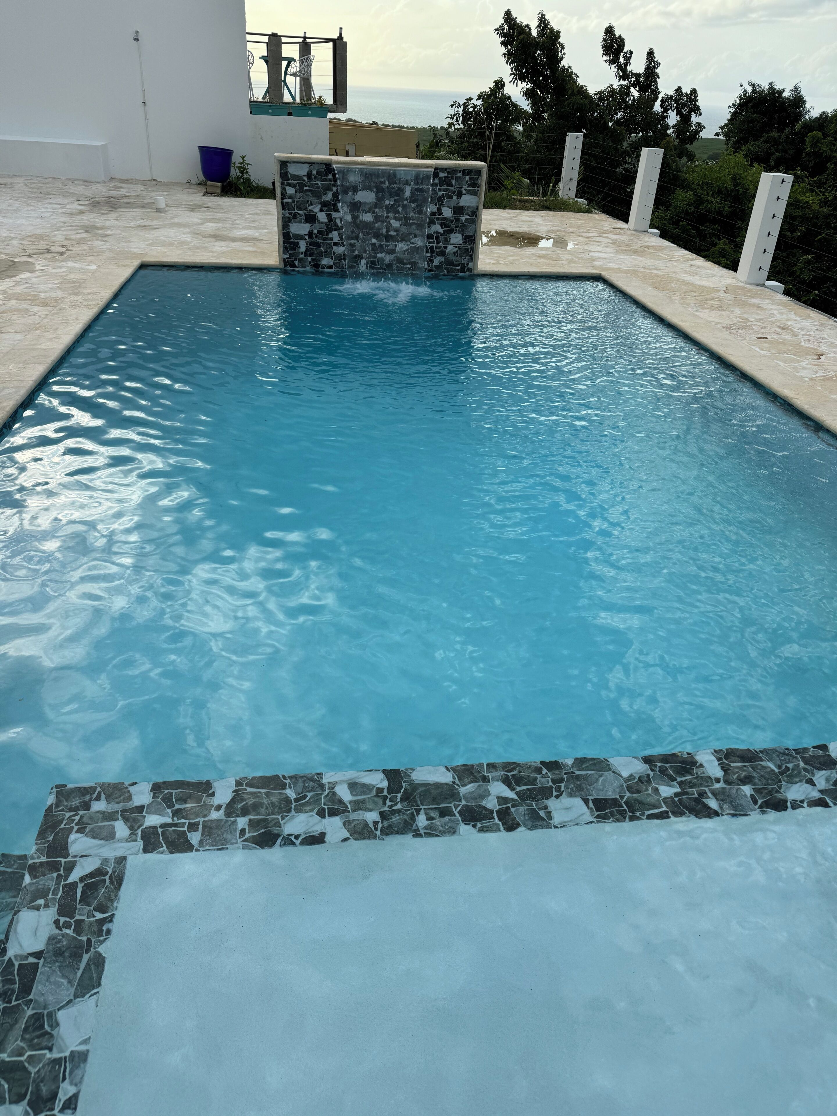 Una piscina con borde de piedra y vistas al mar.