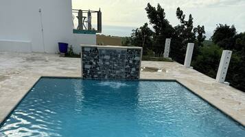 Una piscina con borde de piedra y vistas al mar.