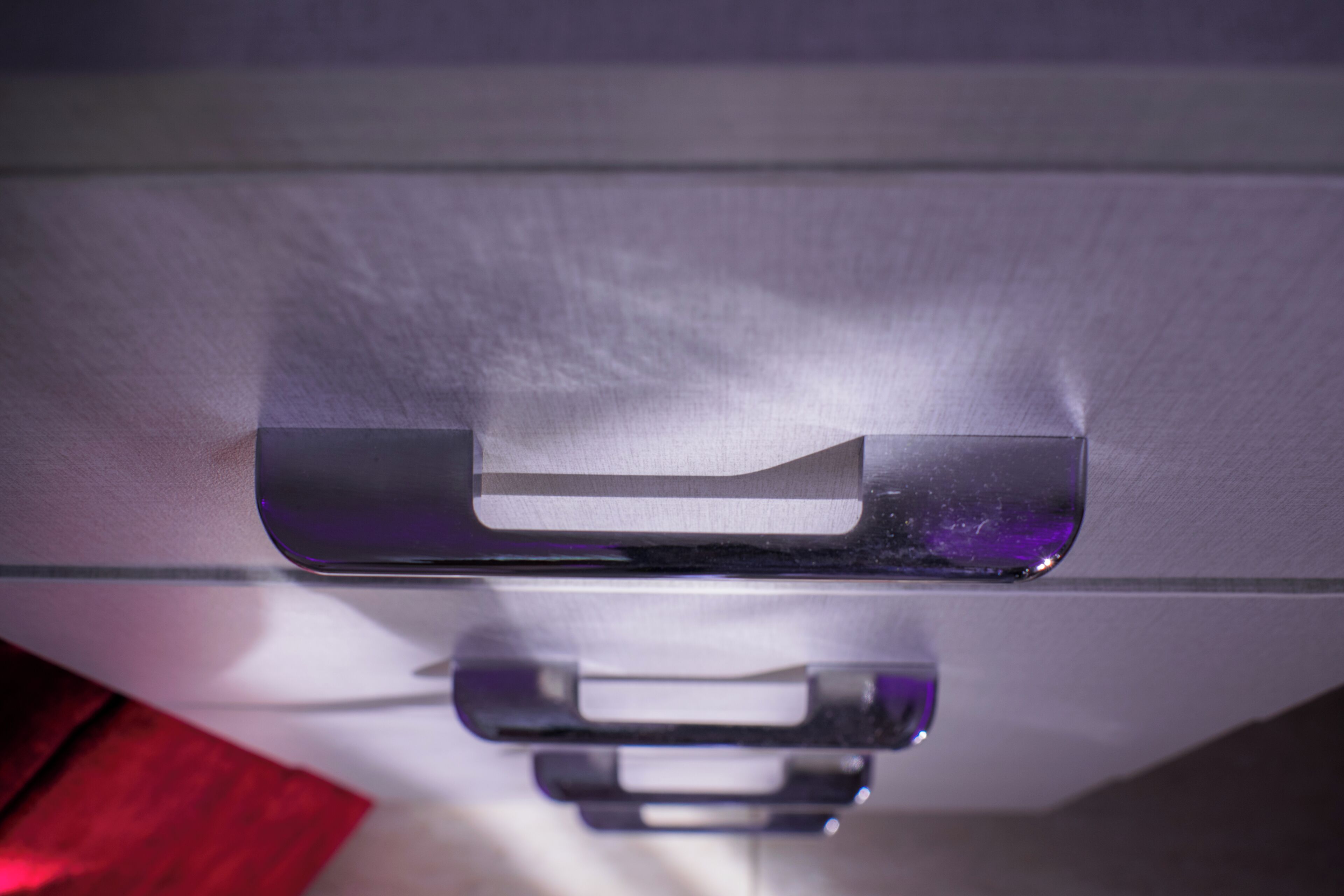 A close-up of a metallic handle on a piece of furniture, likely a cabinet or drawer.