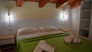 Un dormitorio con colcha verde, dos mesitas de noche y un aparador de madera.