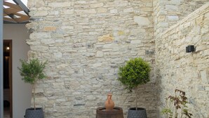 A stone courtyard with potted plants and a rustic barrel.