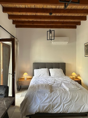 Une chambre à coucher comprenant un lit, deux lampes de chevet, un ventilateur de plafond et un climatiseur fixé au mur.