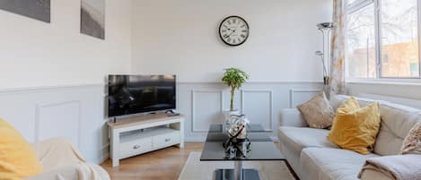 Un salon moderne avec un téléviseur, un canapé et une table basse.