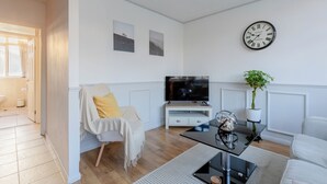 A modern living room with a television, a clock, and a plant. - Quaint 1BD Flat with Balcony in Maida Vale (Greater London)
