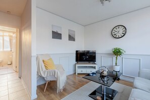 A modern living room with a television, a clock, and a plant. - Quaint 1BD Flat with Balcony in Maida Vale (Greater London)