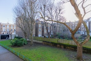 A residential area with a tree-lined street, brick buildings, and a fence. - Quaint 1BD Flat with Balcony in Maida Vale (Greater London)