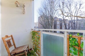 A balcony with a wooden chair, a white railing, and a view of buildings and trees. - Quaint 1BD Flat with Balcony in Maida Vale (Greater London)