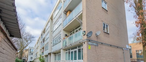 Un immeuble résidentiel à plusieurs étages, doté de balcons, de paraboles de réception par satellite et d’un panneau indiquant la présence d’un système de vidéosurveillance.