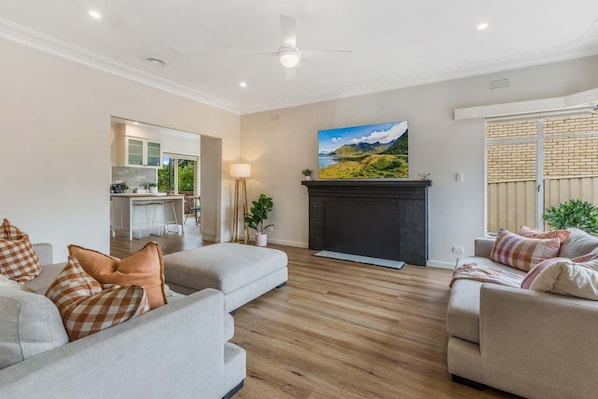 A living room with two sofas, a fireplace, and a kitchen visible through an open door. - Ironbark Rise, Central Bendigo (Ironbark)