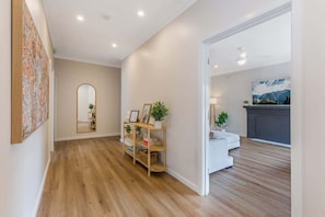 A modern interior with a wooden floor, a white sofa, a fireplace, and a large painting on the wall. - Ironbark Rise, Central Bendigo (Ironbark)