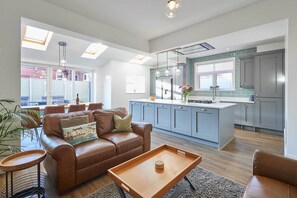 A modern kitchen with grey cabinets, a central island, and pendant lighting.