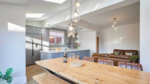 A modern kitchen with a large island, pendant lighting, and a dining area with a bench.