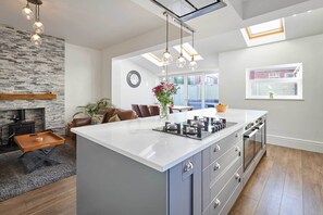 A modern kitchen with a large island, built-in oven, and pendant lighting.