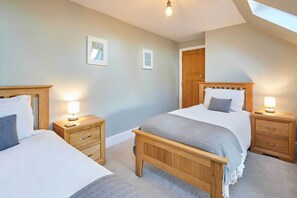A bedroom with two beds, wooden headboards, bedside tables with lamps, and a skylight. - Host & Stay | Peasholm Place (Scarborough)