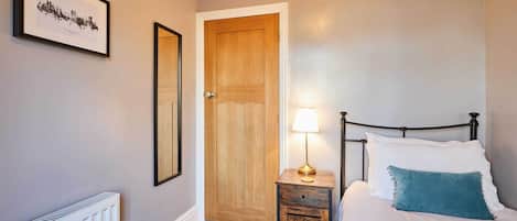 A bedroom with a bed, bedside table, lamp, and a door.