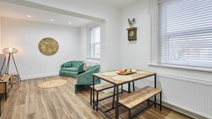 Un salon moderne avec un plancher en bois, un canapé vert, une table basse en bois et une horloge murale.