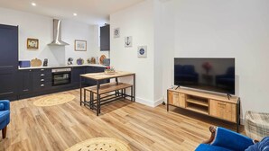 Una cocina moderna con armarios oscuros, una campana extractora de acero inoxidable y una mesa de comedor de madera.