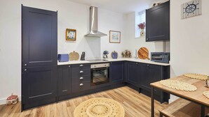 Una cocina moderna con gabinetes oscuros, una campana extractora de acero inoxidable, un microondas y una mesa de madera con un mantel tejido.