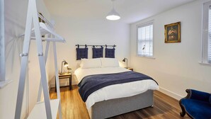 Un dormitorio con cama, una escalera, un escritorio, una silla y una ventana con persianas.