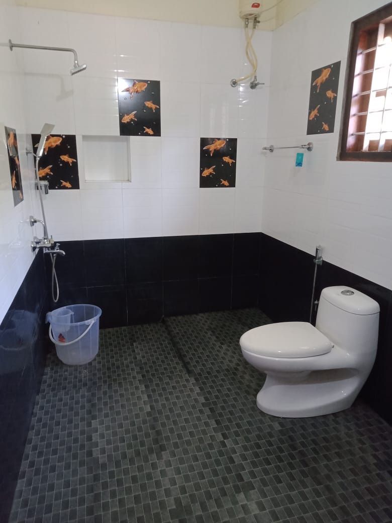 Une salle de bain avec des toilettes blanches, une douche et un sol carrelé.