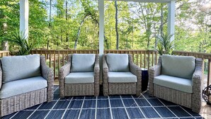 A covered outdoor seating area with wicker chairs and a checkered rug.