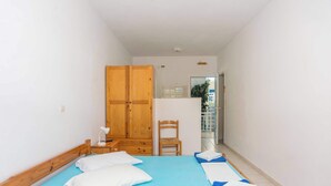 A bedroom with a bed, a wooden wardrobe, a chair, and a desk with a lamp. - BlueWhite Studio - Cozy Garden Getaway (Kerameies)