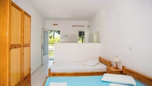 A bedroom with a large wardrobe, a bed with a blue bedspread, and a nightstand with a lamp. - BlueWhite Studio - Getaway by the Pool (Kerameies)