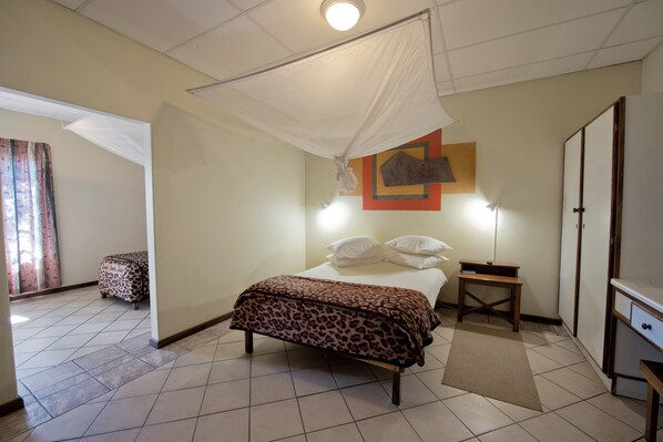 Un dormitorio con cama, mesita de noche, armario y una ventana con cortinas.