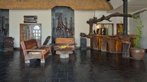 Un hall con techo de paja, muebles de madera, una recepción y una estatua de jirafa.