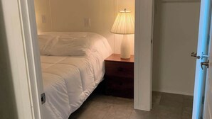 Un dormitorio con cama, mesita de noche, lámpara y armario.