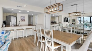 Cocina moderna con refrigerador de acero inoxidable, muebles blancos y una isla integrada con taburetes de bar.