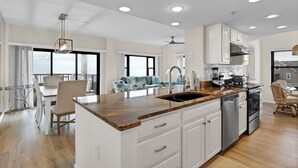 Una cocina amplia con una isla central, armarios blancos y electrodomésticos de acero inoxidable.