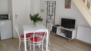 A compact living space with a dining table, chairs, a small kitchenette, a television, and a staircase. - Rose Garden Bayeux (Bayeux)