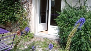 A small, enclosed garden area with a bench and a door leading to a room. - Rose Garden Bayeux (Bayeux)